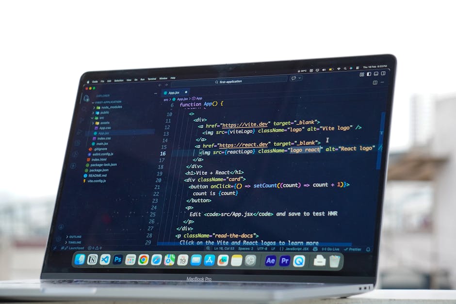 A close-up view of a MacBook Pro laptop displaying a dark-themed code editor window, with lines of HTML and JavaScript code visible on the screen. The code includes tags such as <div>, <a>, <img>, and